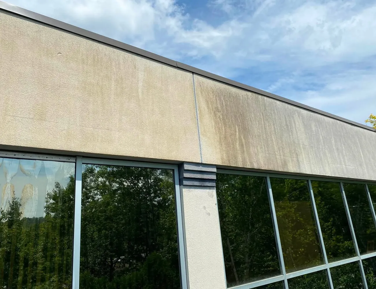 Weather-stained concrete and glass on a commercial building before cleaning