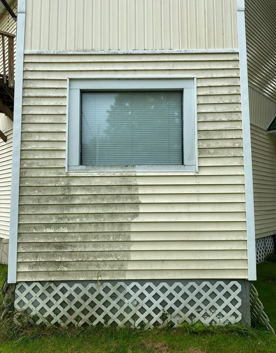 Vinyl siding mid-wash, the cleaned half beside the dirty half
