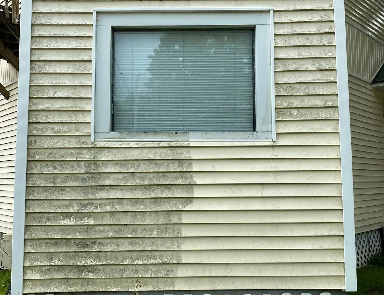 Vinyl siding part-way through a wash, showing the cleaned section beside the dirty one