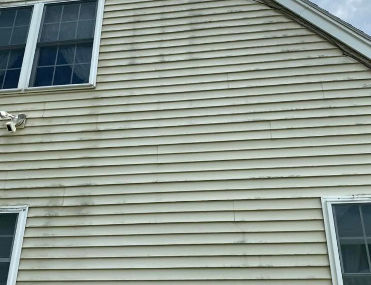 A gable end with heavy algae streaking before cleaning